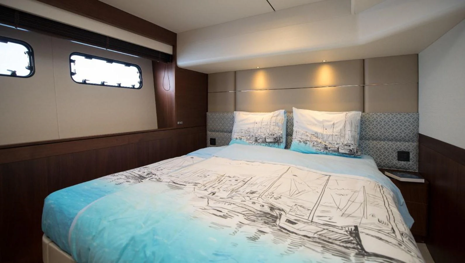 A cozy stateroom featuring a comfortable bed with nautical-themed bedding and soft lighting. aboard RAGARDA Yacht for Sale