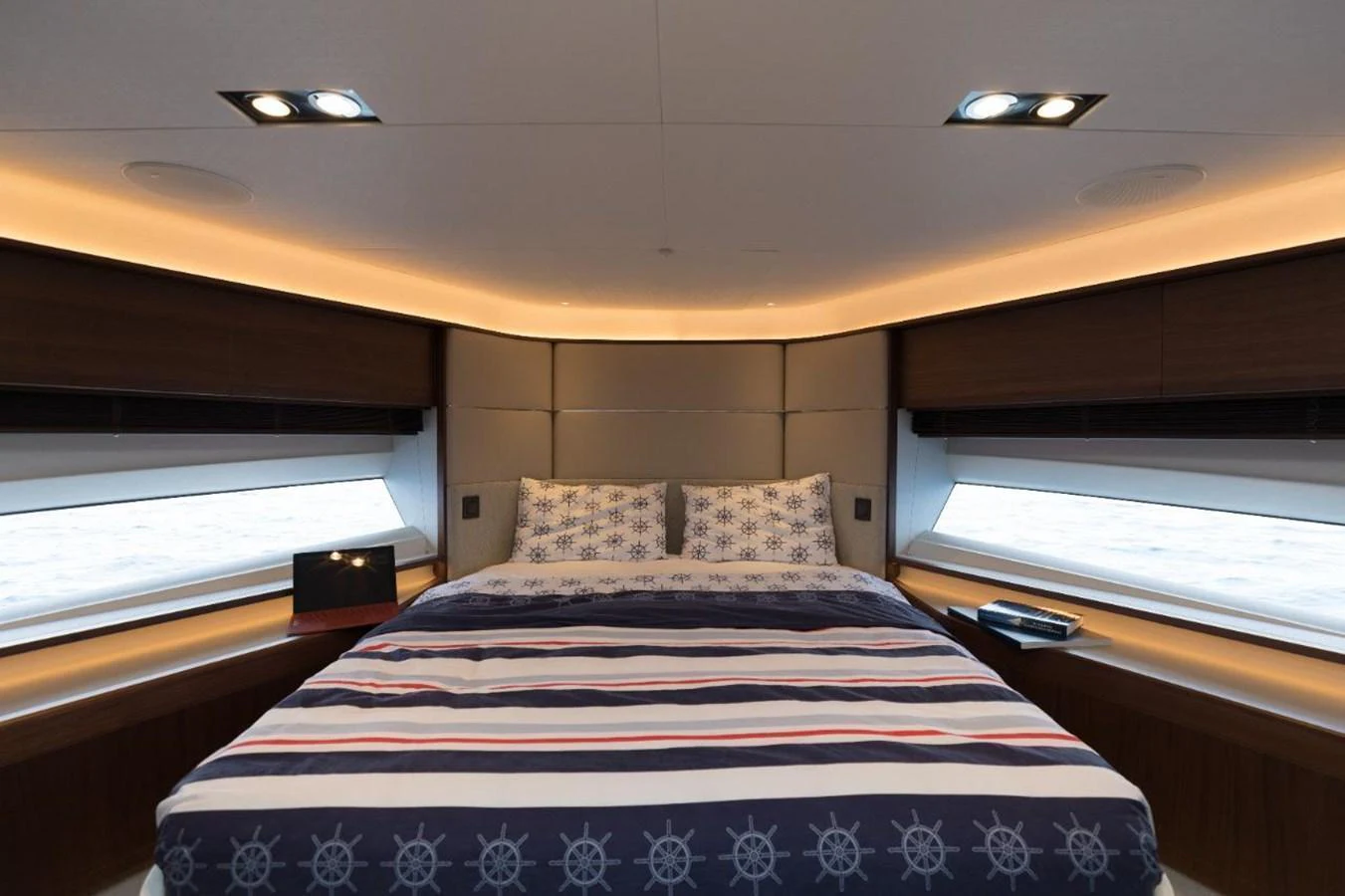 The stateroom features a luxurious bed with nautical-themed bedding and ample natural light from the surrounding windows. aboard RAGARDA Yacht for Sale