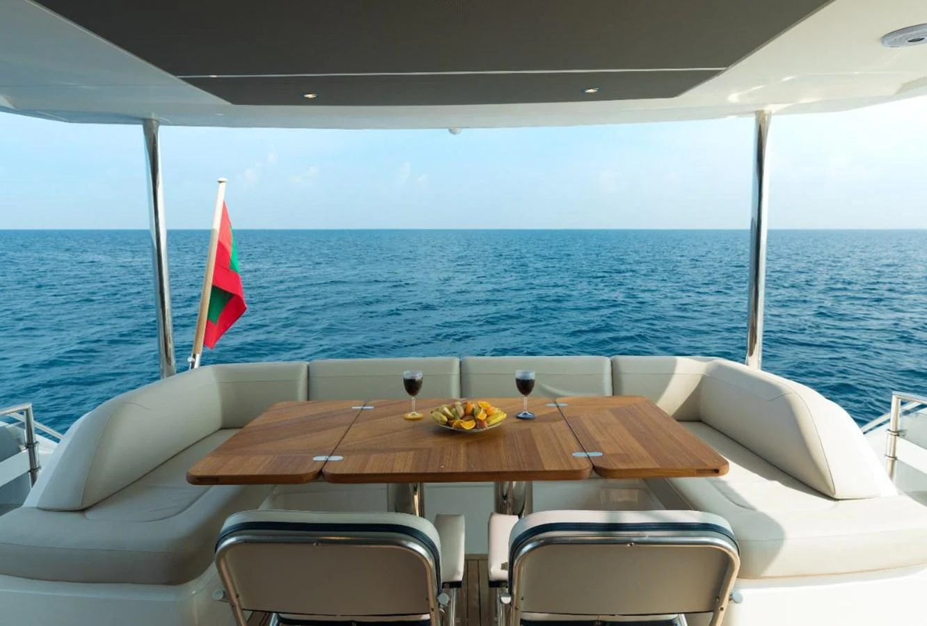 The aft deck features a cozy dining area with a wooden table and comfortable seating, perfect for enjoying meals with a view of the open sea. aboard RAGARDA Yacht for Sale