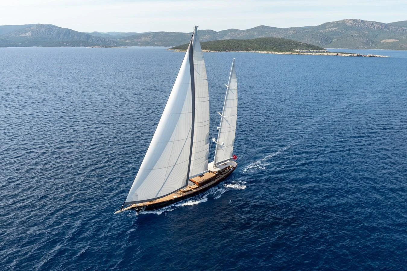 A stunning sailing yacht glides gracefully through the open sea with its sails fully unfurled. aboard SALLYNA Yacht for Sale