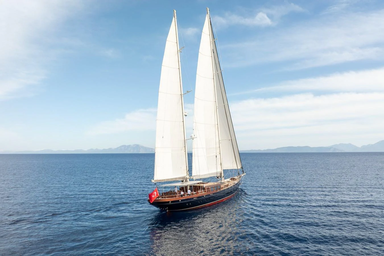 A stunning sailing yacht glides gracefully on calm blue waters under a clear sky. aboard SALLYNA Yacht for Sale