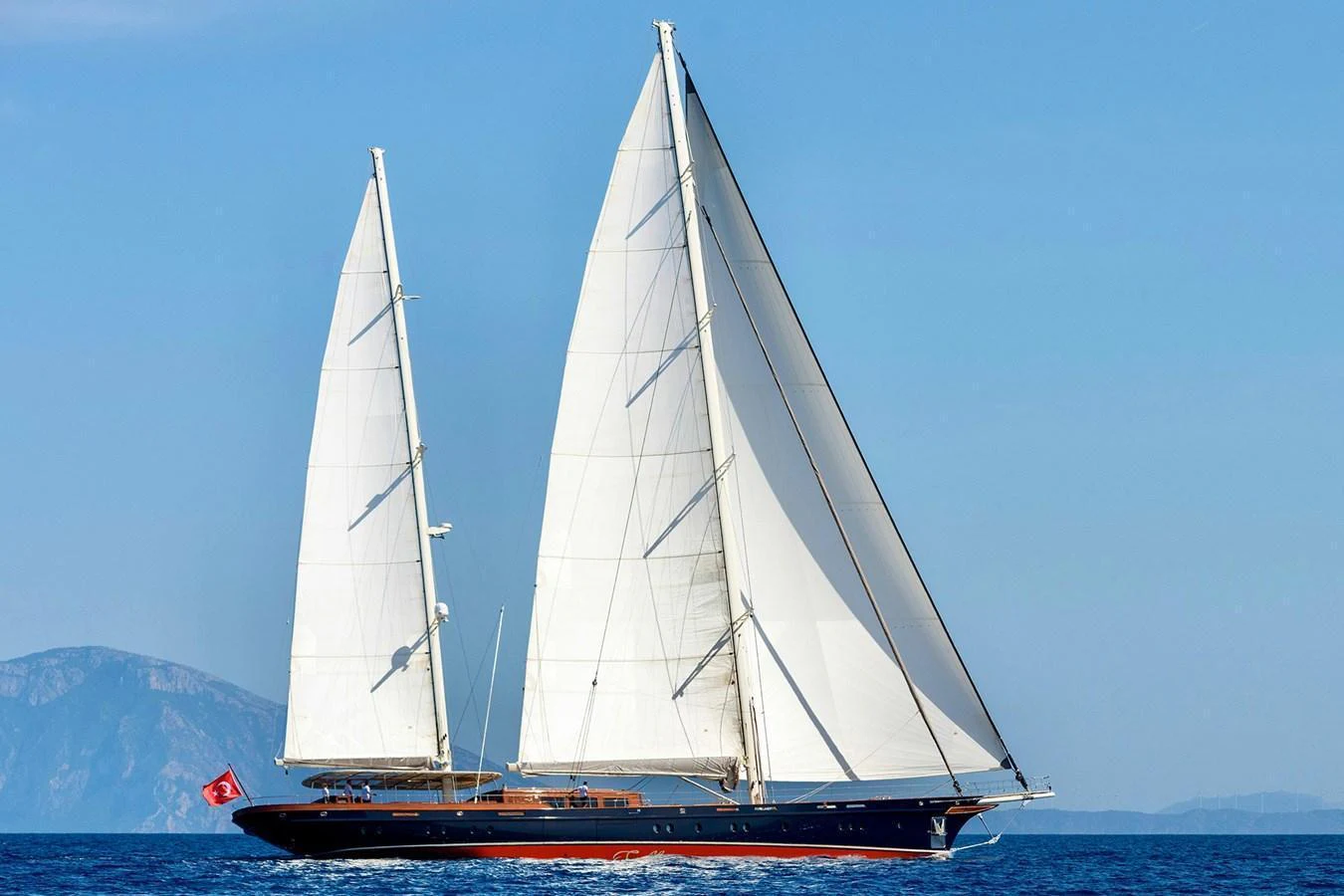 A stunning sailing yacht glides gracefully over the calm blue sea with its sails fully unfurled. aboard SALLYNA Yacht for Sale