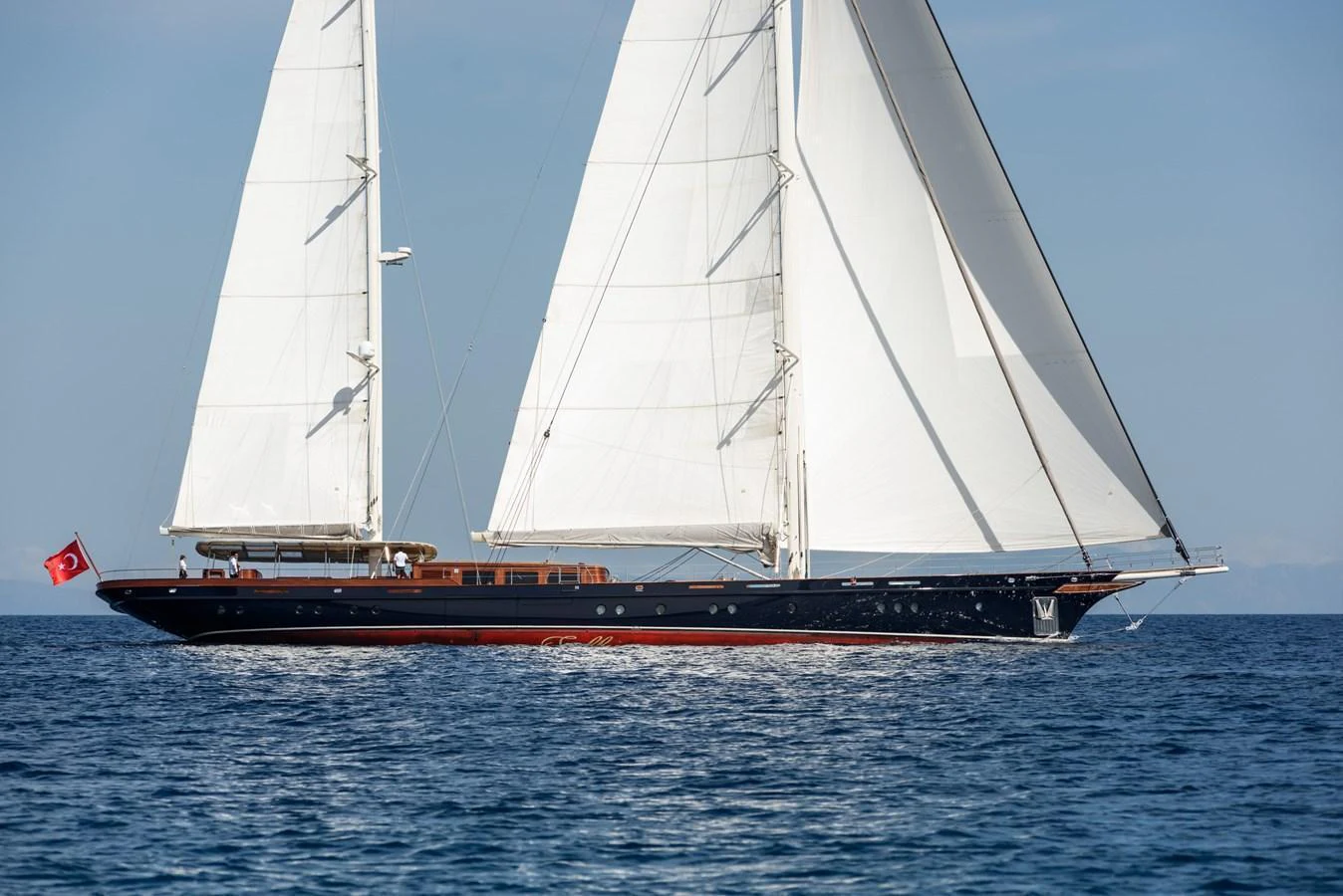 A stunning sailing yacht glides gracefully on the open sea with full sails. aboard SALLYNA Yacht for Sale