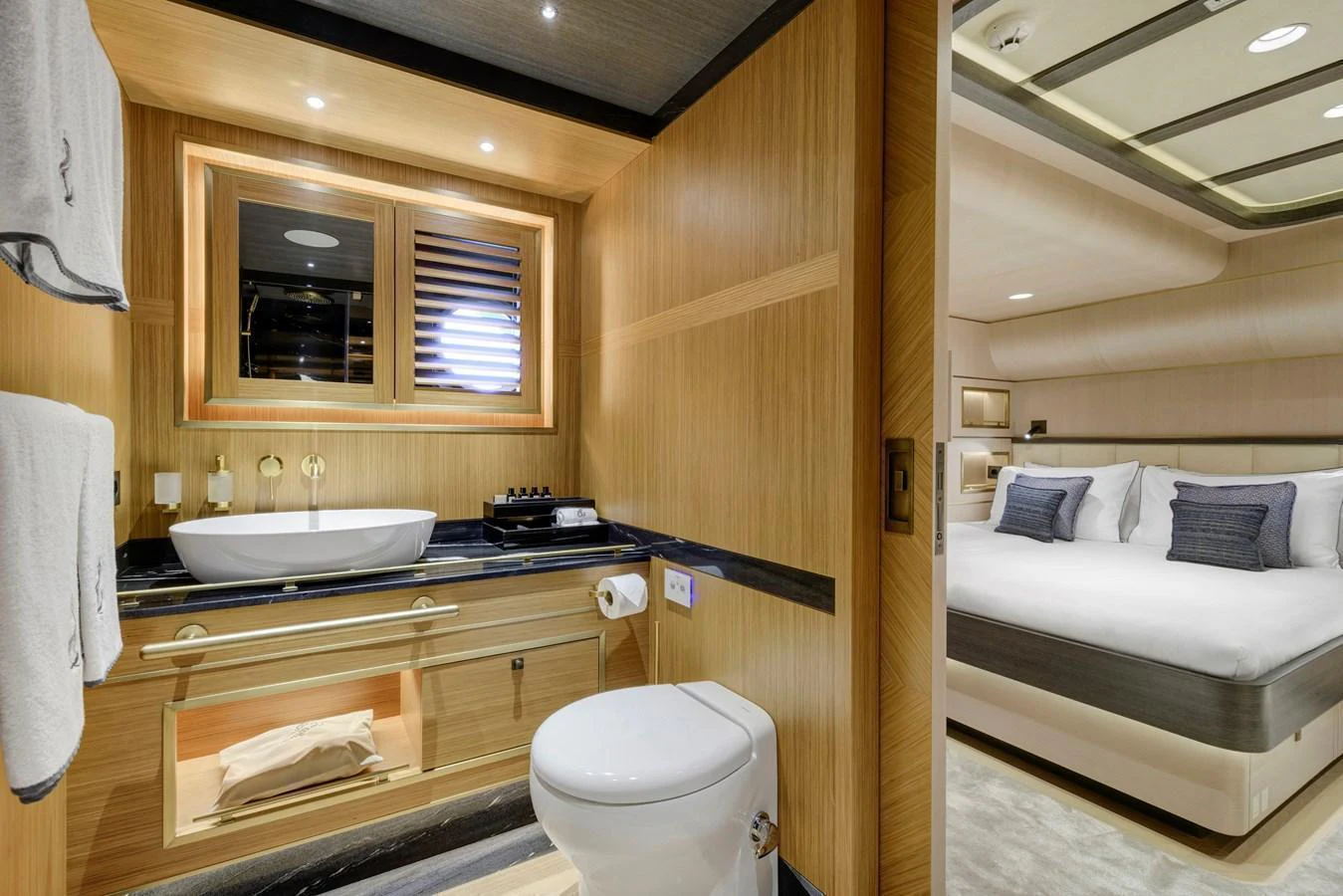 The image showcases a luxurious bathroom and adjacent stateroom with elegant wood finishes and modern amenities. aboard SALLYNA Yacht for Sale