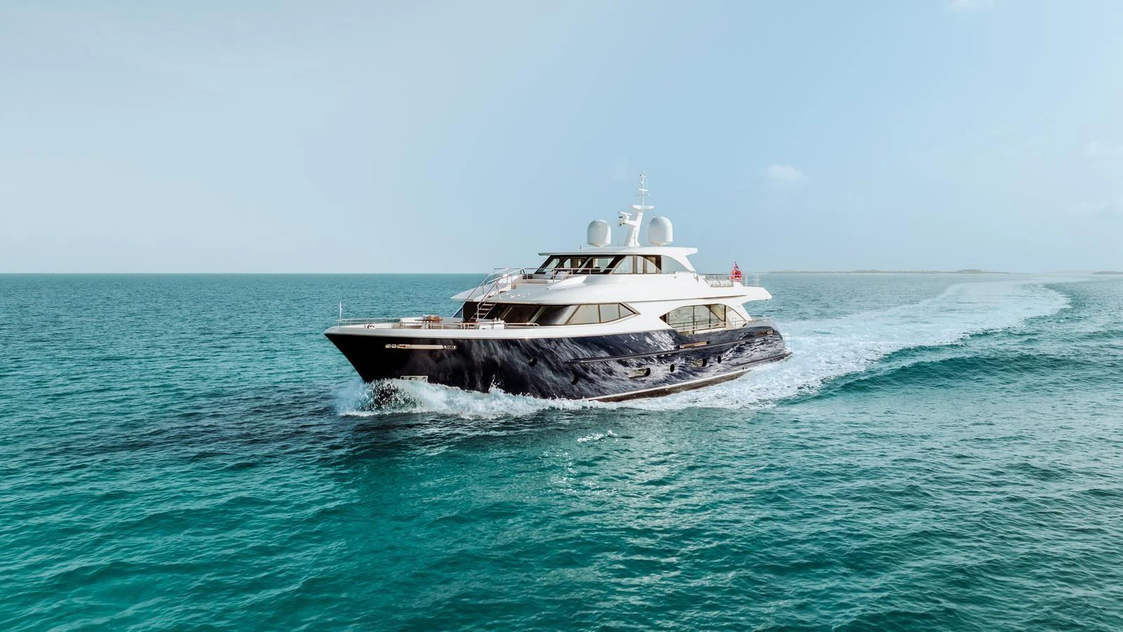 A sleek and elegant yacht cruises through calm, turquoise waters under a clear sky. aboard MIDNIGHT SAGA Yacht for Sale