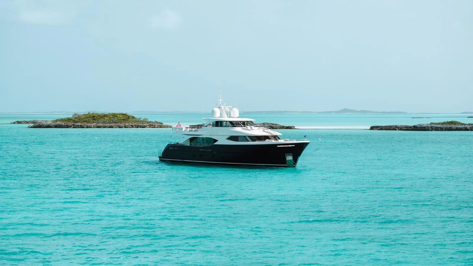 A sleek yacht cruises through turquoise waters near a picturesque island. aboard MIDNIGHT SAGA Yacht for Sale