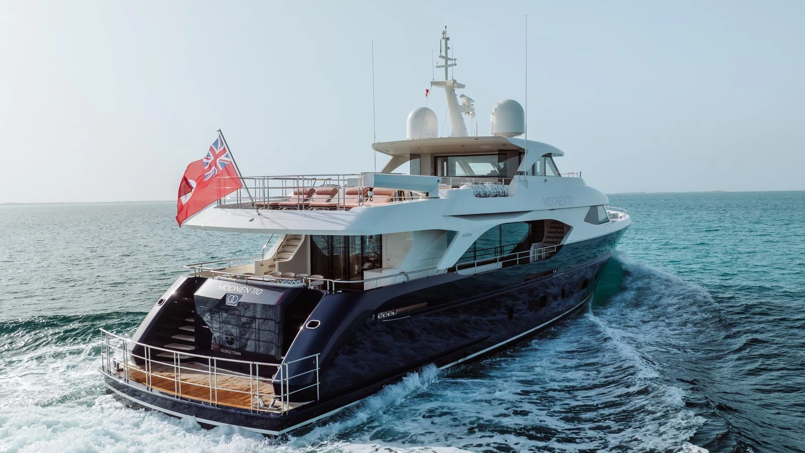 A sleek and modern yacht cruising on the open sea with a flag waving at the stern. aboard MIDNIGHT SAGA Yacht for Sale