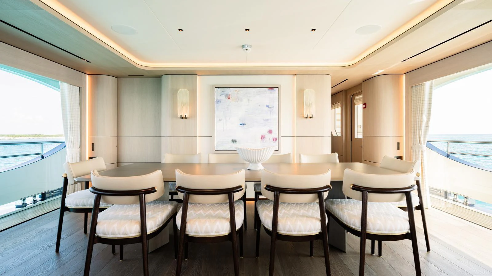 The yacht's dining area features a large table with elegant chairs, surrounded by panoramic windows offering stunning sea views. aboard MIDNIGHT SAGA Yacht for Sale