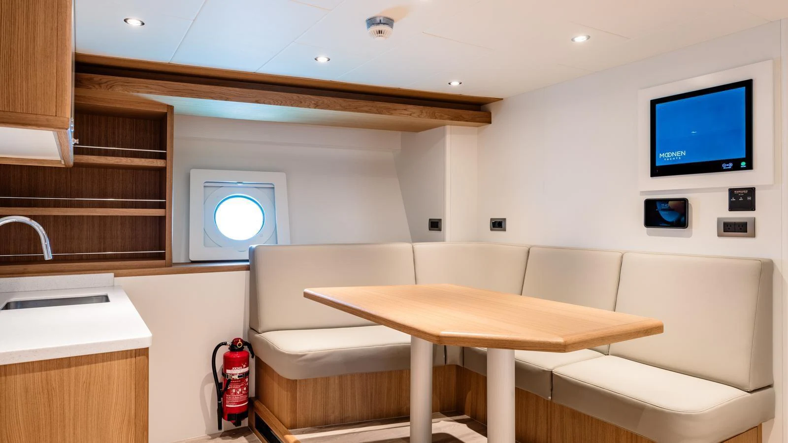 The yacht's interior features a cozy dining area with a built-in seating arrangement and a small porthole window. aboard MIDNIGHT SAGA Yacht for Sale
