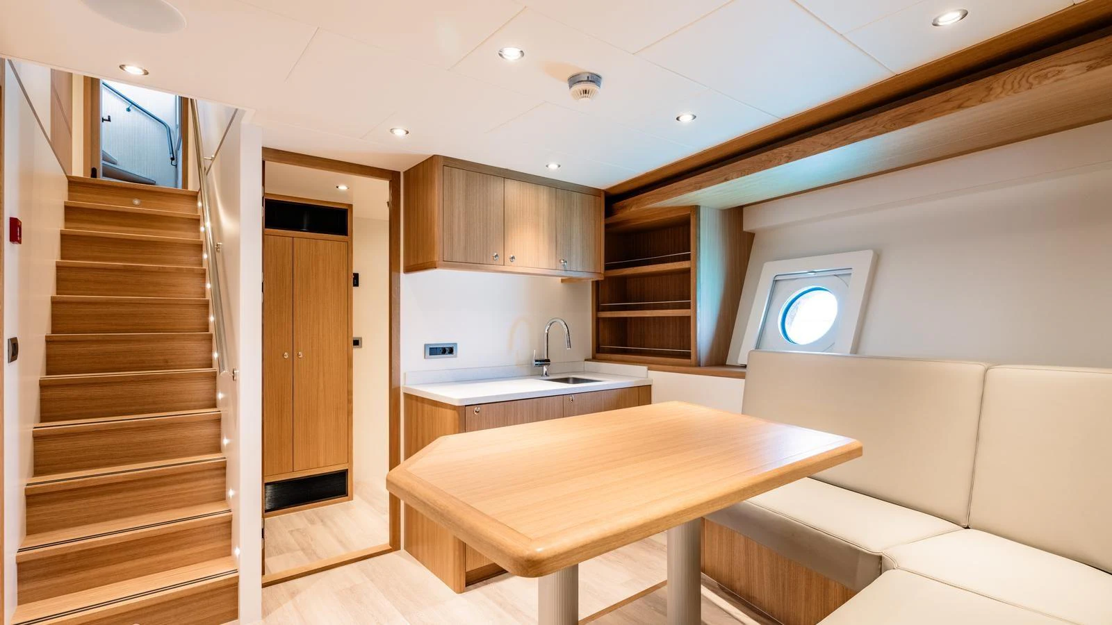 The saloon features a cozy seating area with a table, wooden cabinetry, and a staircase leading to the upper deck. aboard MIDNIGHT SAGA Yacht for Sale
