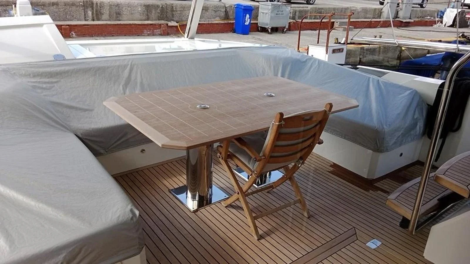 The aft deck features a cozy dining area with a wooden table and chairs, perfect for alfresco meals. aboard VIRTUS Yacht for Sale