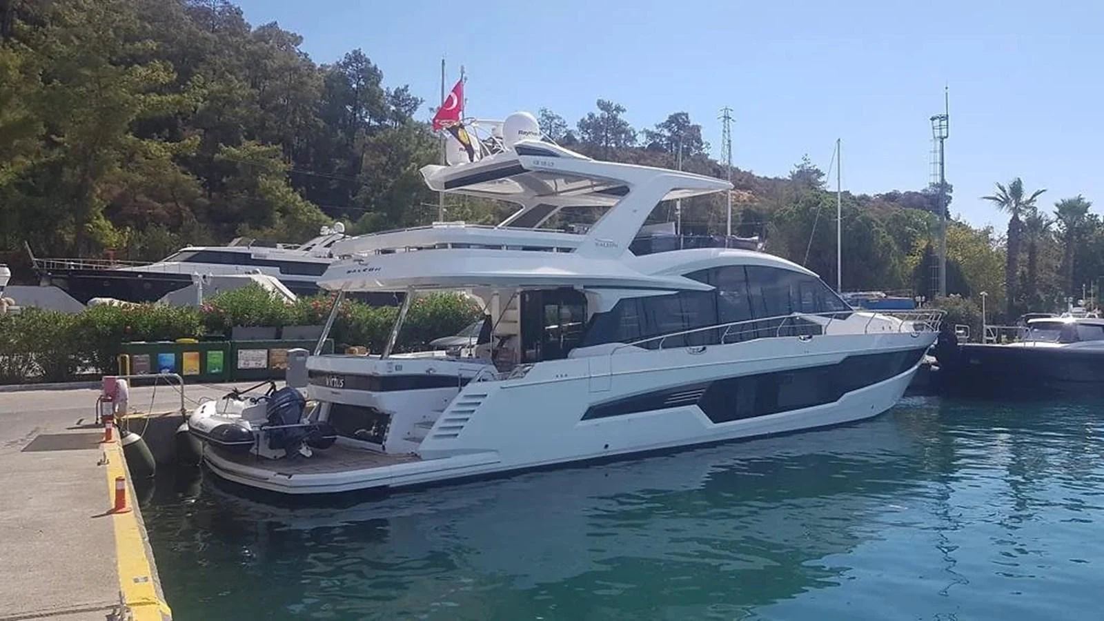 A sleek and modern yacht is docked at a marina, showcasing its elegant design and spacious decks. aboard VIRTUS Yacht for Sale