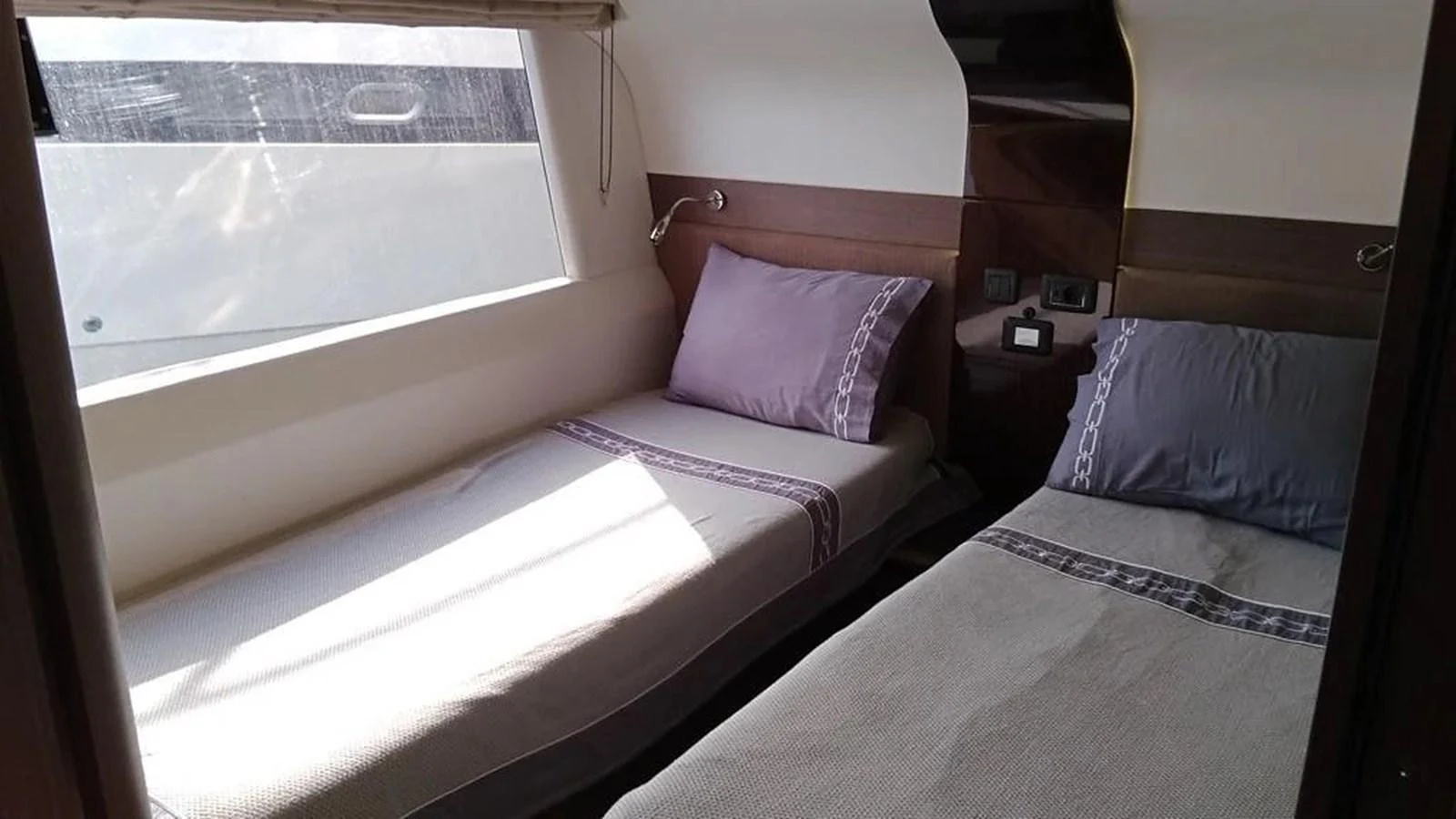 The twin stateroom features two comfortable single beds with elegant bedding and ample natural light. aboard VIRTUS Yacht for Sale