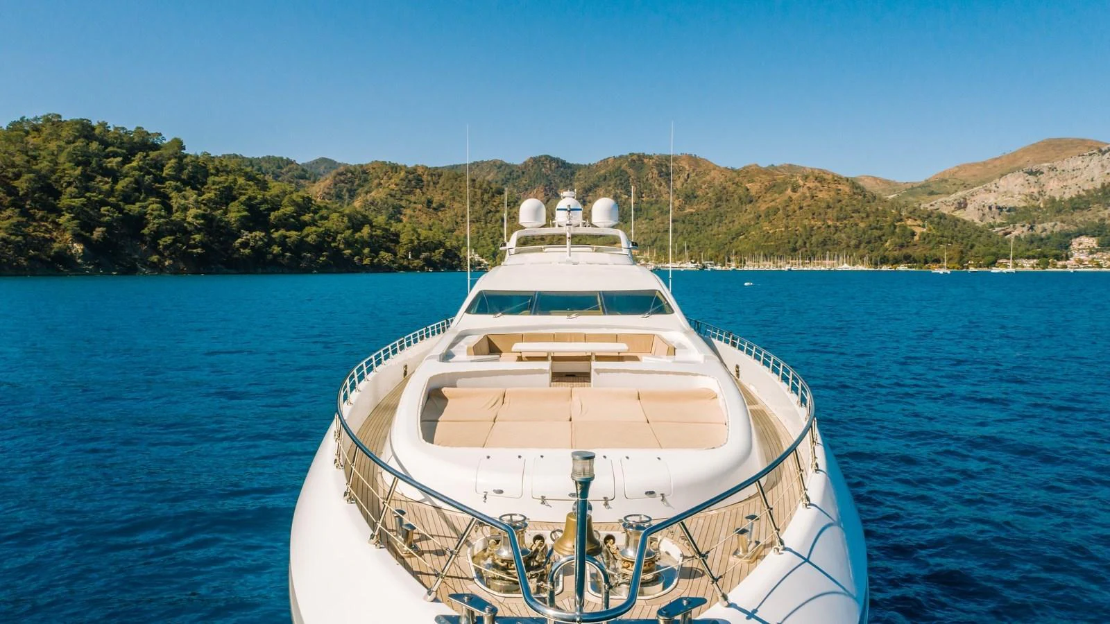 A luxurious yacht is anchored in a serene bay with a stunning mountainous backdrop. aboard SEA PEARL Yacht for Sale