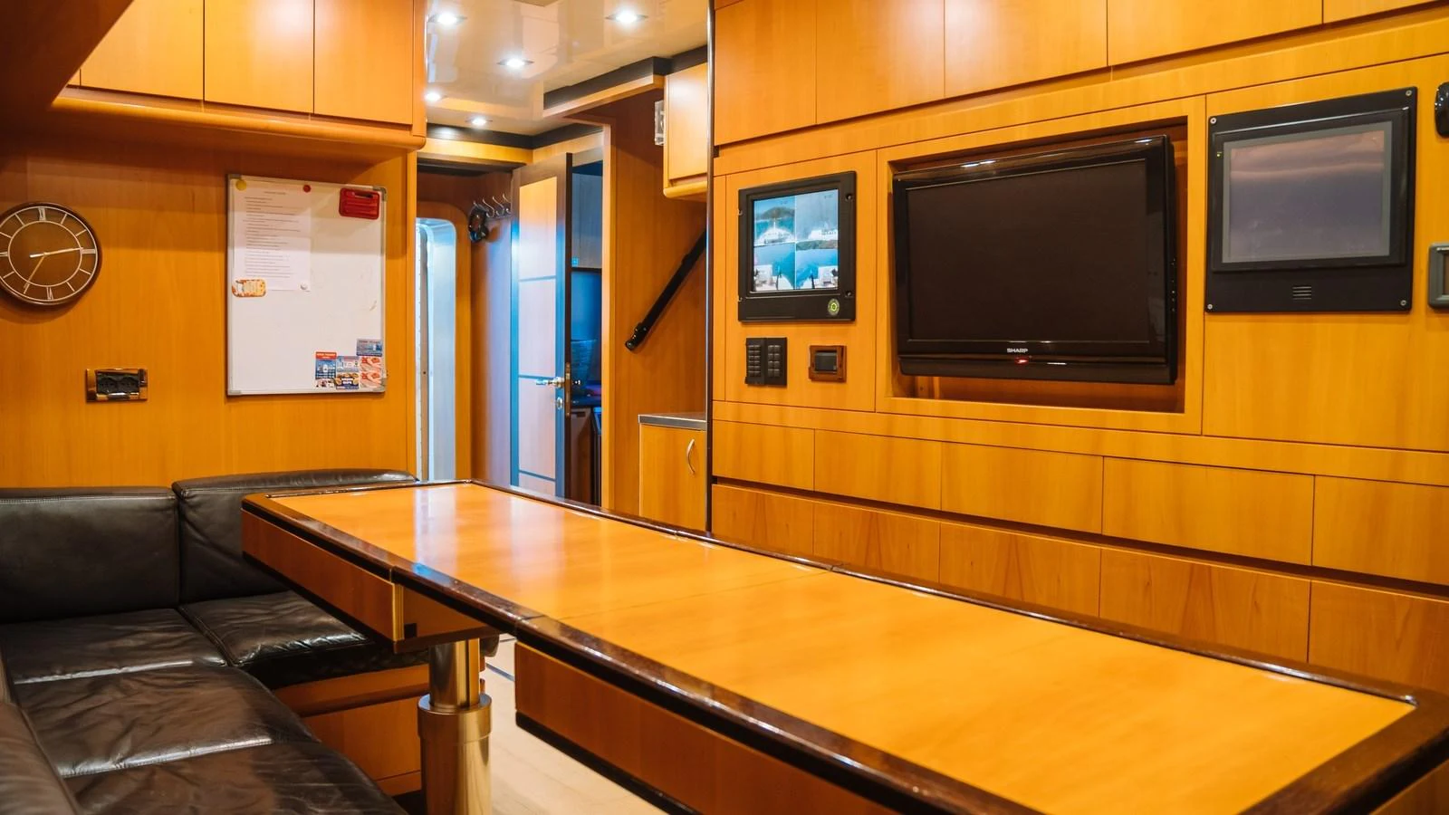 The salon features a sleek wooden table, leather seating, and modern entertainment systems. aboard SEA PEARL Yacht for Sale