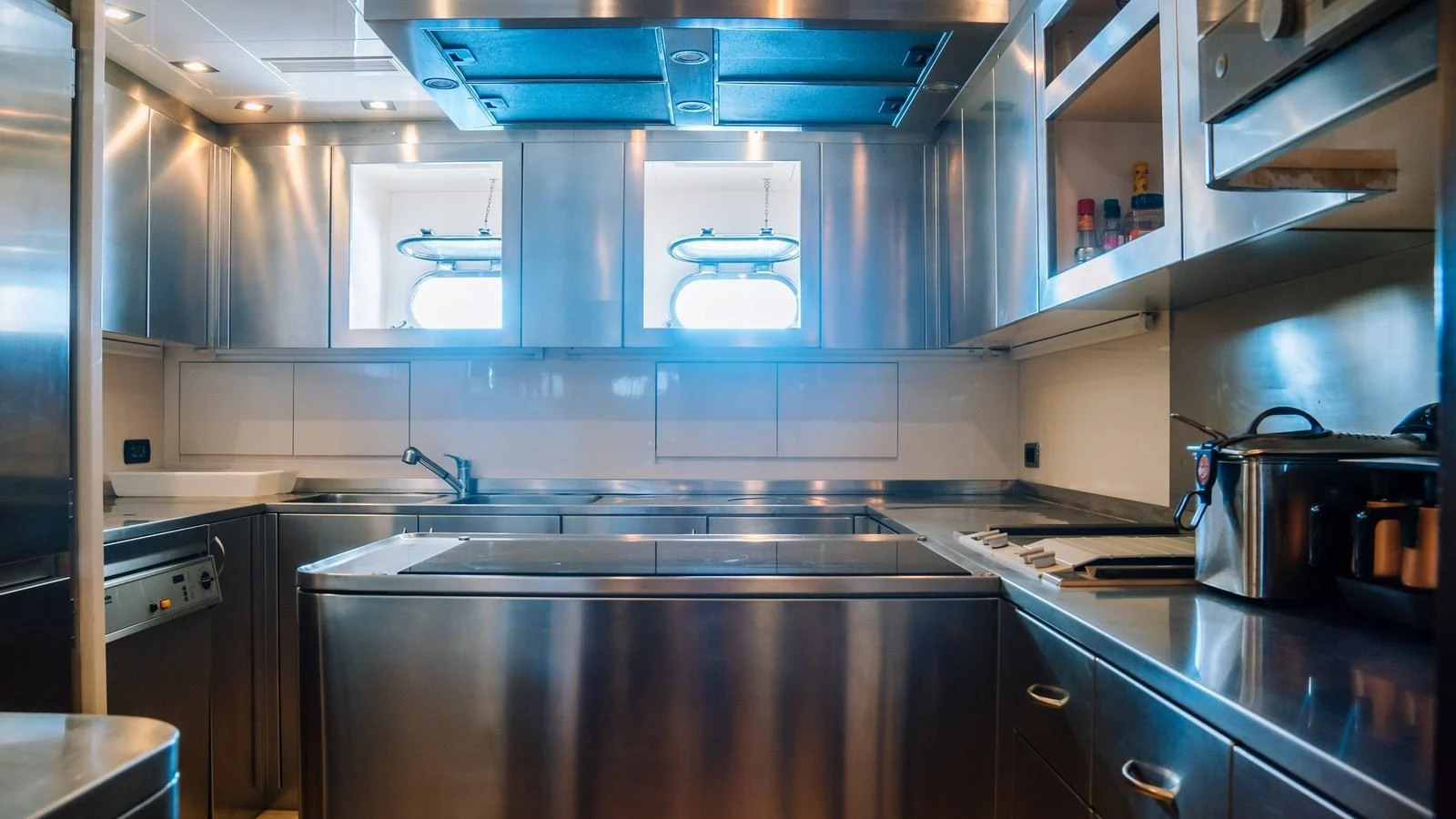 The yacht's galley features sleek stainless steel appliances and ample counter space, illuminated by natural light from two portholes. aboard SEA PEARL Yacht for Sale