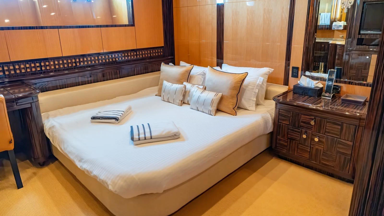 The stateroom features a luxurious bed with elegant bedding and warm wood accents. aboard SEA PEARL Yacht for Sale
