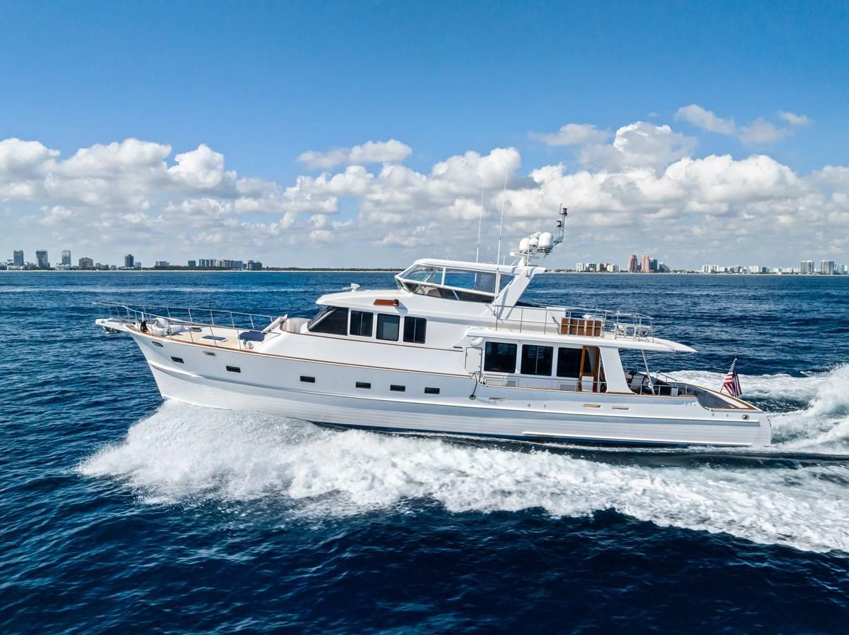A sleek white yacht cruises smoothly on the open water under a clear blue sky. aboard EL LEGADO Yacht for Sale