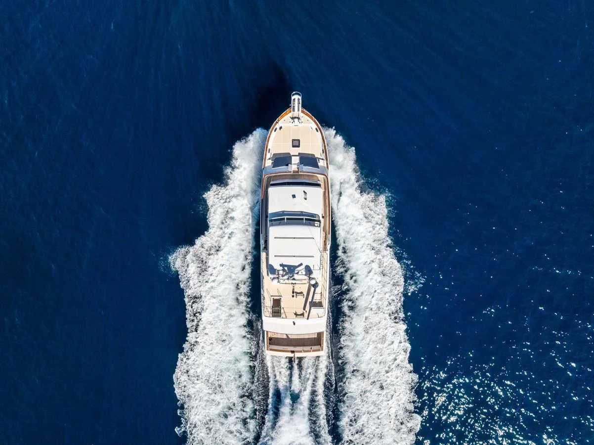 Aerial view of a yacht cruising through deep blue waters, leaving a trail of white wake. aboard EL LEGADO Yacht for Sale
