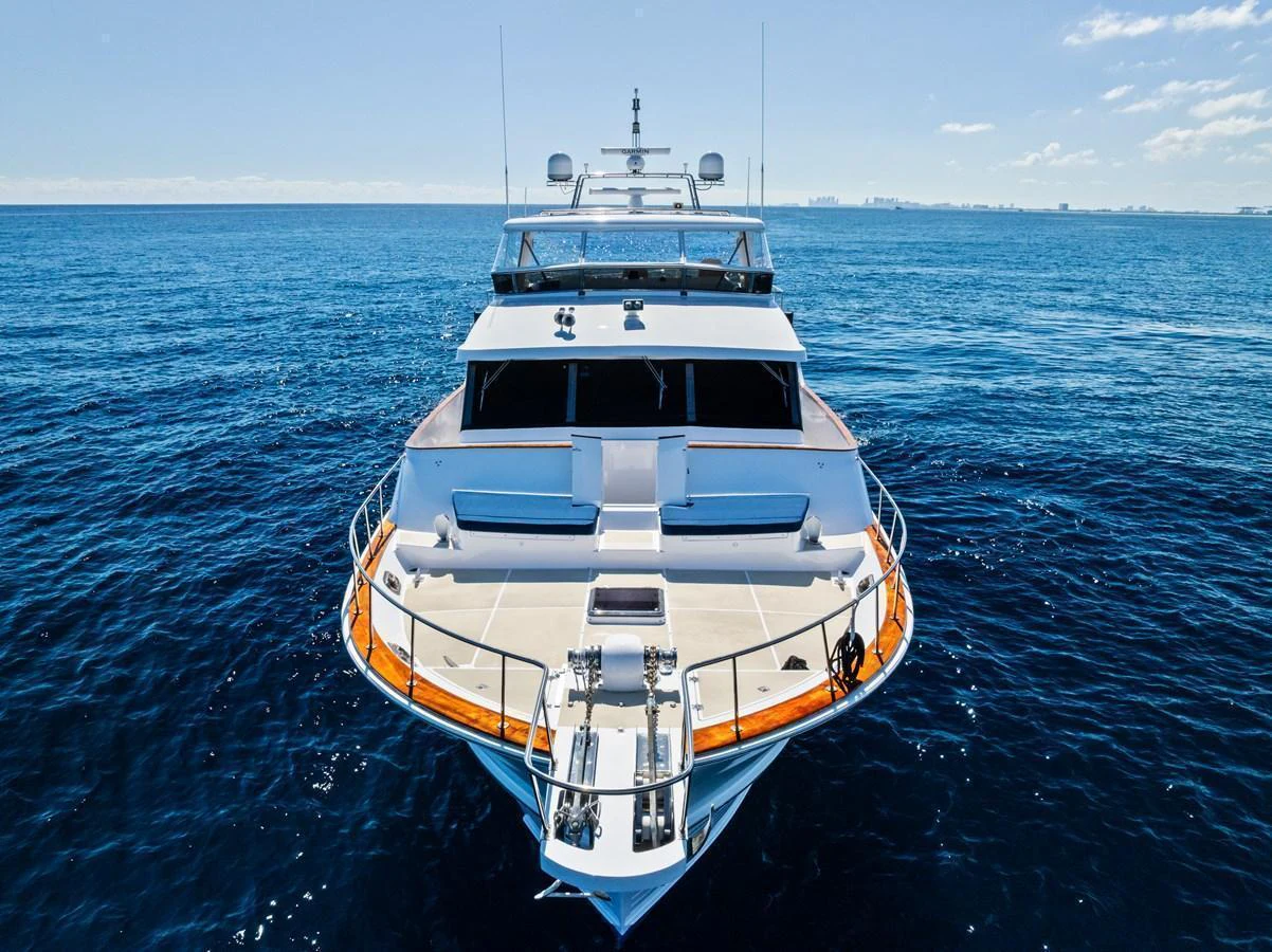 A luxurious yacht is seen head-on, cruising through calm blue waters under a clear sky. aboard EL LEGADO Yacht for Sale