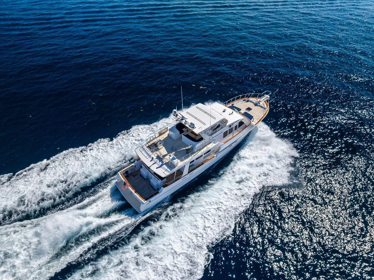 A luxurious yacht cruises through the open sea, leaving a trail of white wake behind. aboard EL LEGADO Yacht for Sale