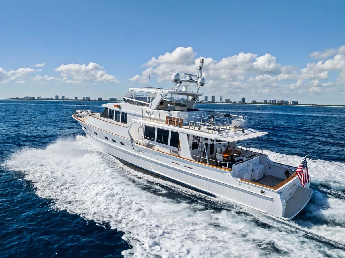 A sleek yacht cruises through the open water under a clear blue sky. aboard EL LEGADO Yacht for Sale
