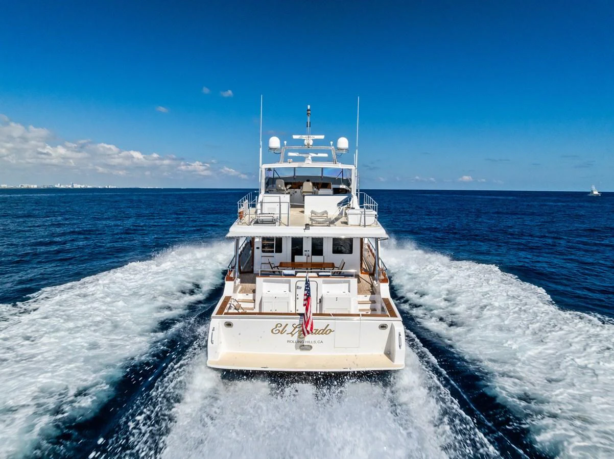 A luxurious yacht cruises through the open sea, leaving a trail of white wake behind. aboard EL LEGADO Yacht for Sale