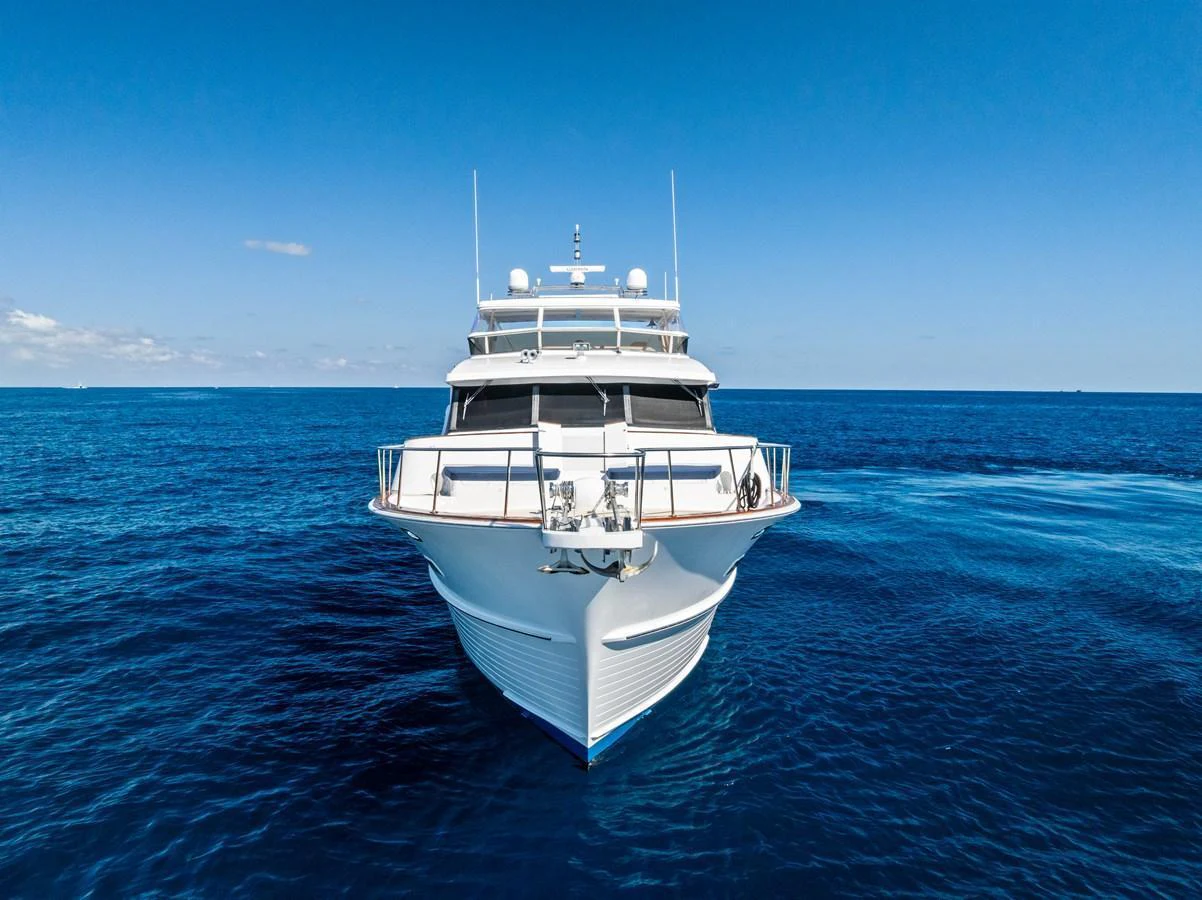 A stunning yacht is captured head-on, cruising through the deep blue sea under a clear sky. aboard EL LEGADO Yacht for Sale