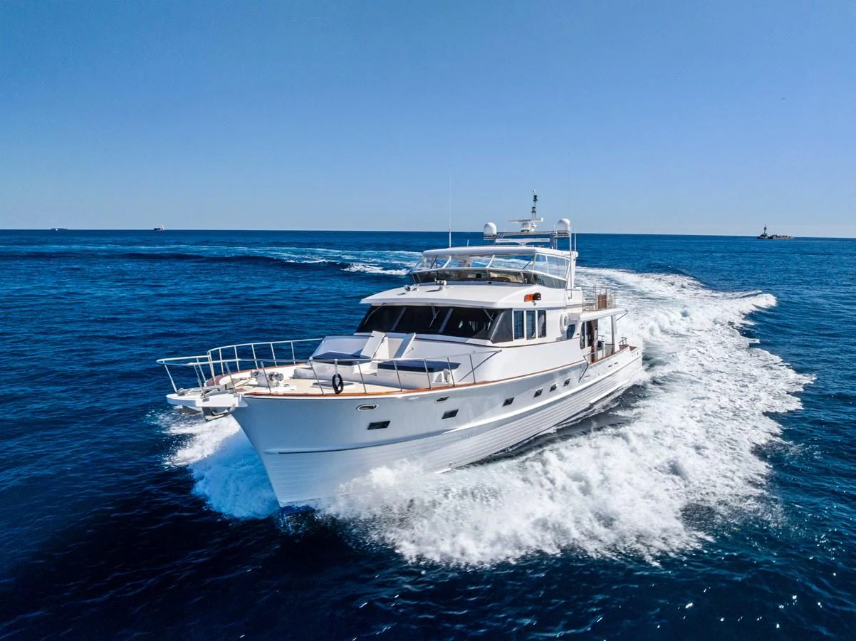 A luxurious yacht cruises through the open sea under a clear blue sky. aboard EL LEGADO Yacht for Sale