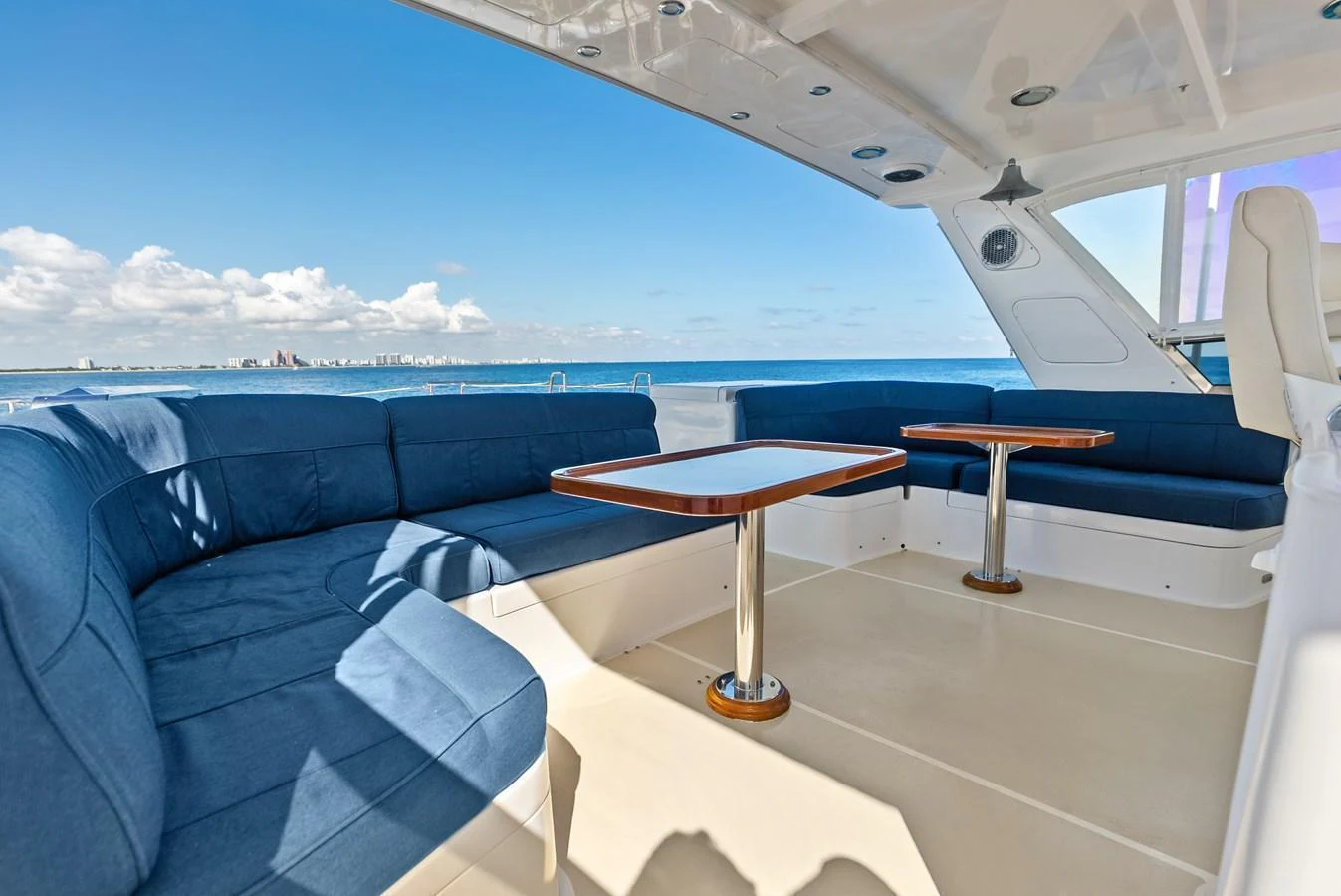 The yacht's salon features comfortable blue seating with wooden tables, offering a relaxing space with a view of the sea. aboard EL LEGADO Yacht for Sale