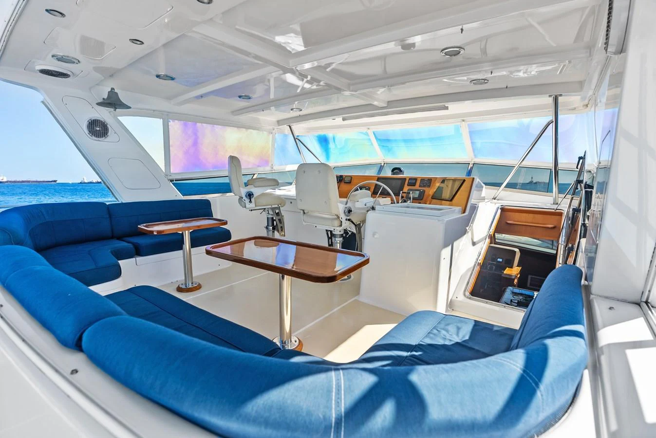 The yacht's helm area features plush blue seating and a well-equipped control station with panoramic views. aboard EL LEGADO Yacht for Sale