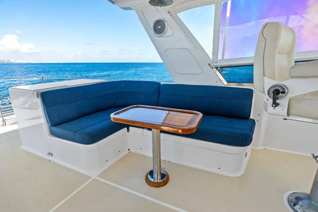 The flybridge features a comfortable seating area with a sleek wooden table, perfect for enjoying the ocean views. aboard EL LEGADO Yacht for Sale