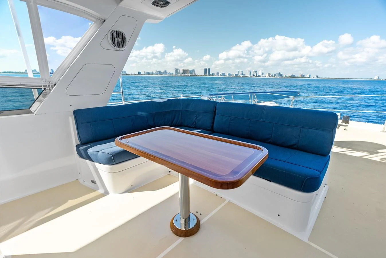 The aft deck features a comfortable seating area with a sleek wooden table, perfect for enjoying the ocean views. aboard EL LEGADO Yacht for Sale