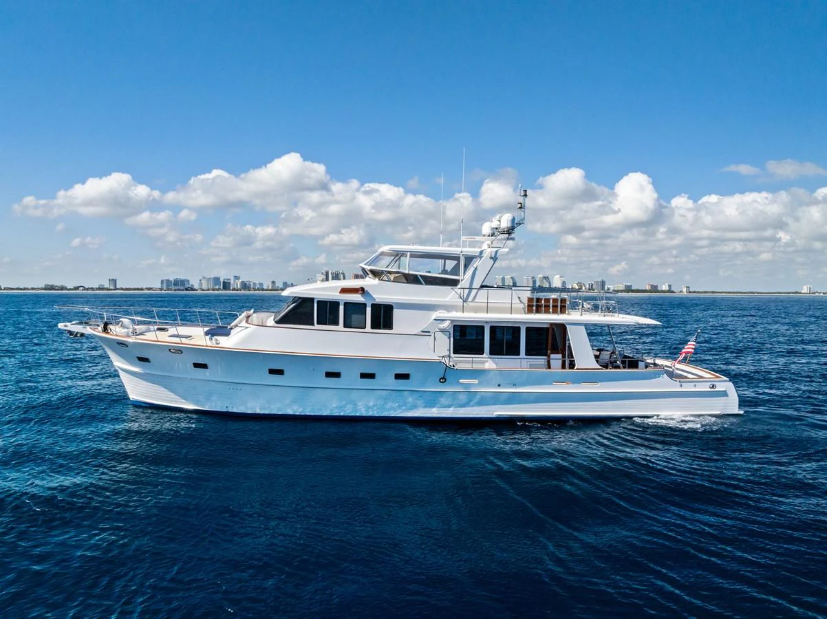 A sleek white yacht cruises on calm blue waters under a clear sky. aboard EL LEGADO Yacht for Sale