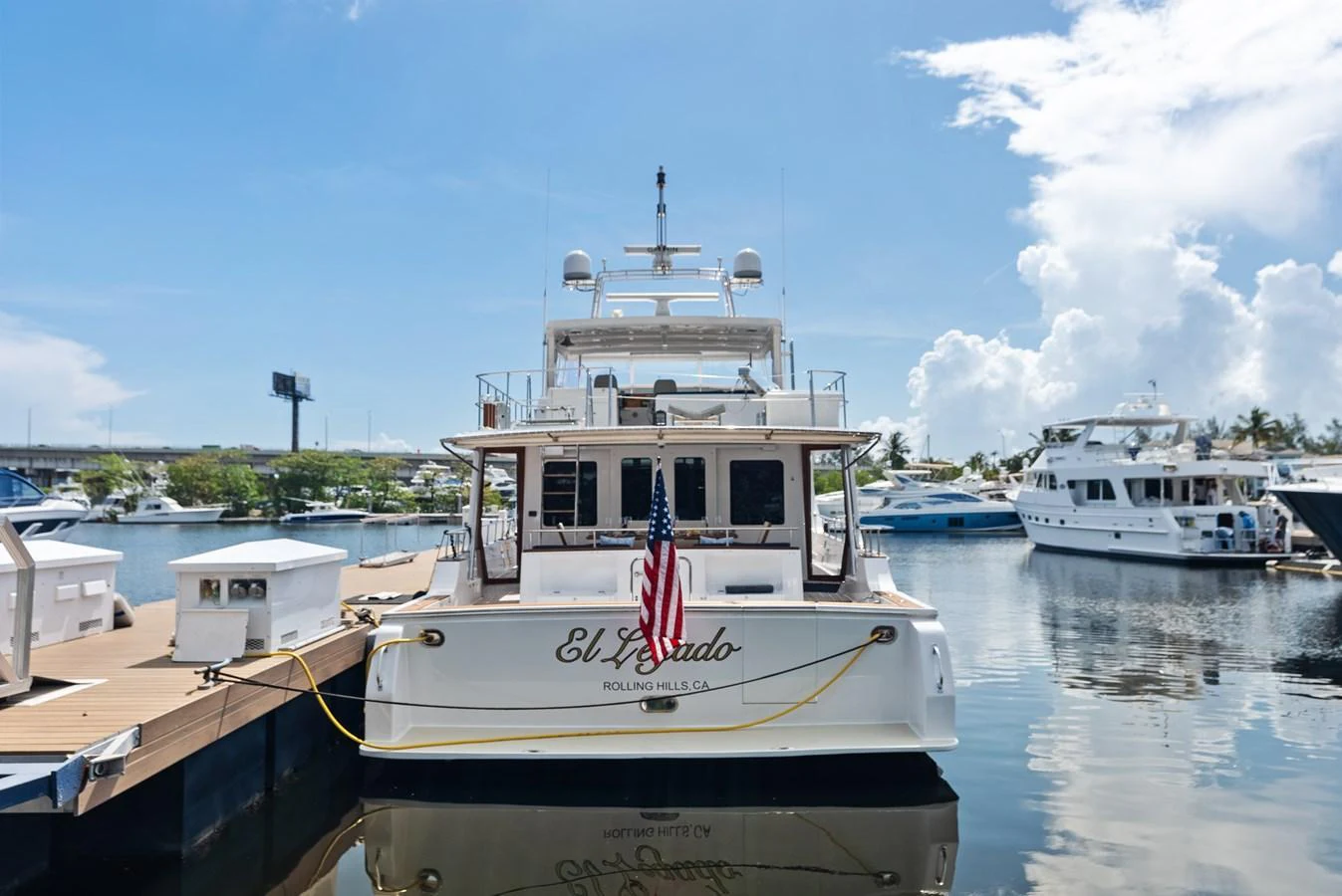A luxurious yacht is docked at a marina, showcasing its elegant stern and inviting outdoor space. aboard EL LEGADO Yacht for Sale