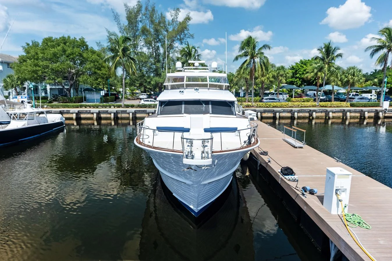 A luxurious yacht is docked at a serene marina, surrounded by lush greenery and palm trees. aboard EL LEGADO Yacht for Sale