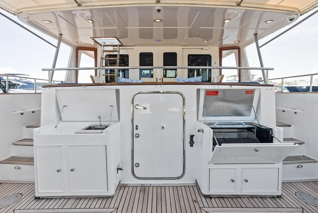 The aft deck features a well-equipped outdoor kitchen area with ample storage and a clean, modern design. aboard EL LEGADO Yacht for Sale