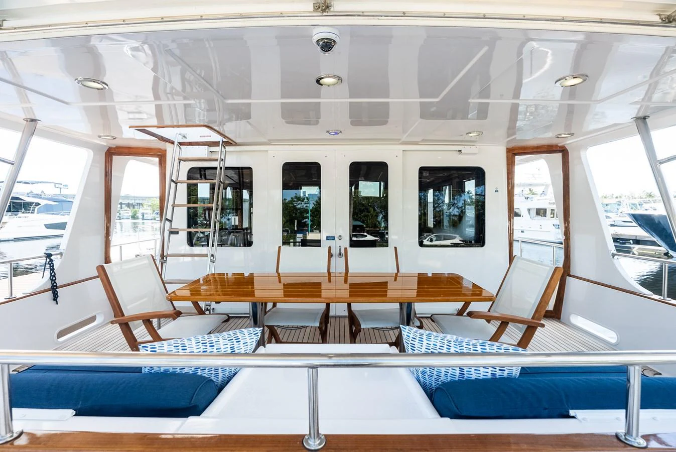 The aft deck features a spacious dining area with wooden furniture and ample seating. aboard EL LEGADO Yacht for Sale