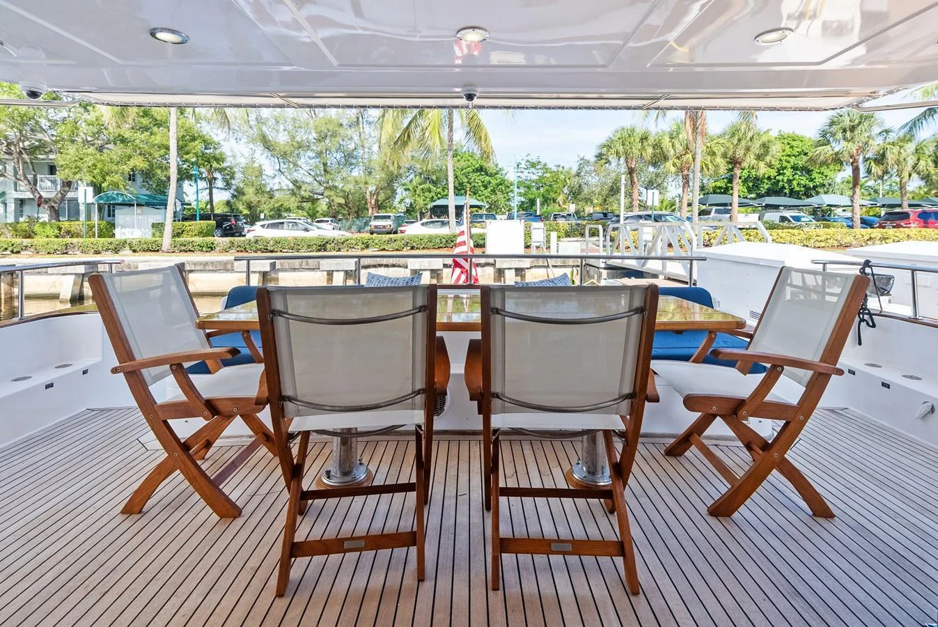 The aft deck features a comfortable dining area with wooden chairs and a view of the surroundings. aboard EL LEGADO Yacht for Sale