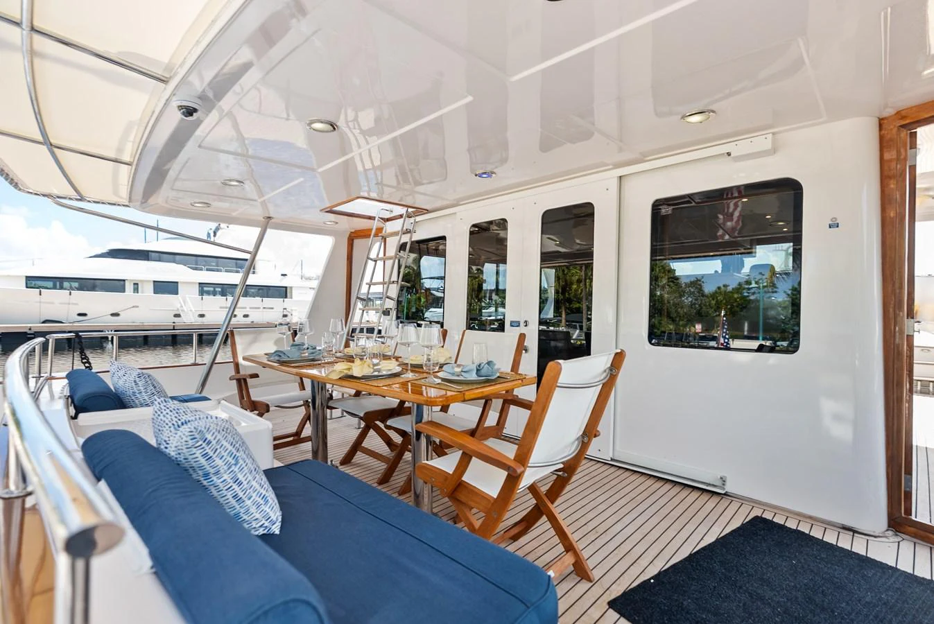 The aft deck features a comfortable dining area with elegant seating and a polished wooden table. aboard EL LEGADO Yacht for Sale