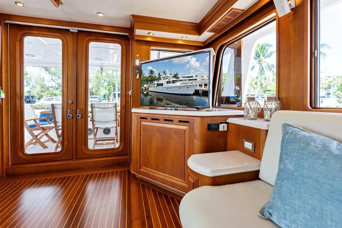 The interior features a cozy seating area with a view of the exterior deck through glass doors. aboard EL LEGADO Yacht for Sale