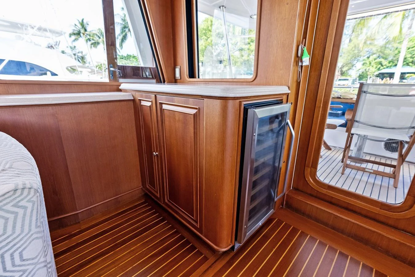 The yacht's interior features elegant wood cabinetry and a built-in wine cooler, with a view of the exterior deck through large windows. aboard EL LEGADO Yacht for Sale