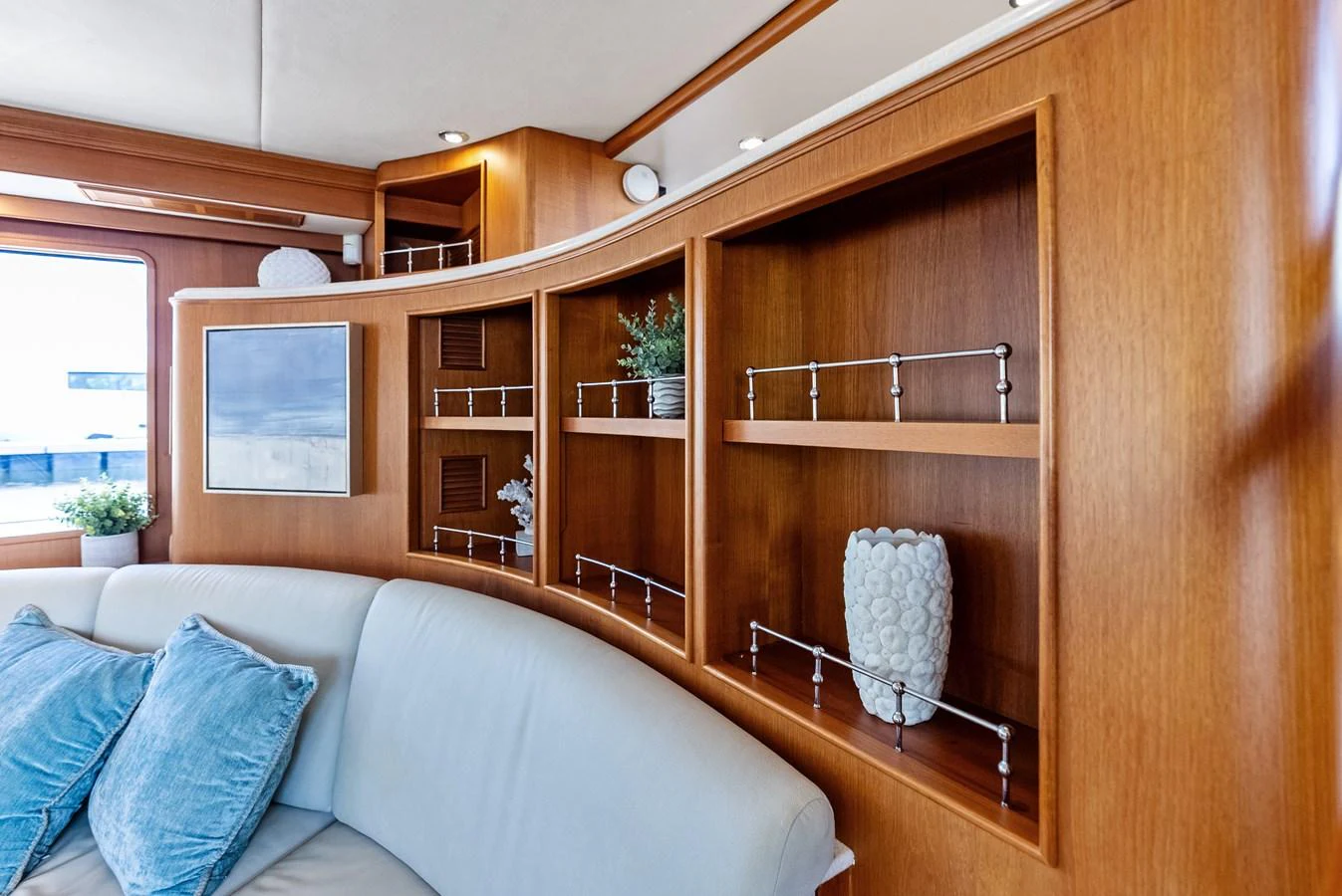 The yacht's interior features elegant wooden shelving and a comfortable seating area with decorative cushions. aboard EL LEGADO Yacht for Sale