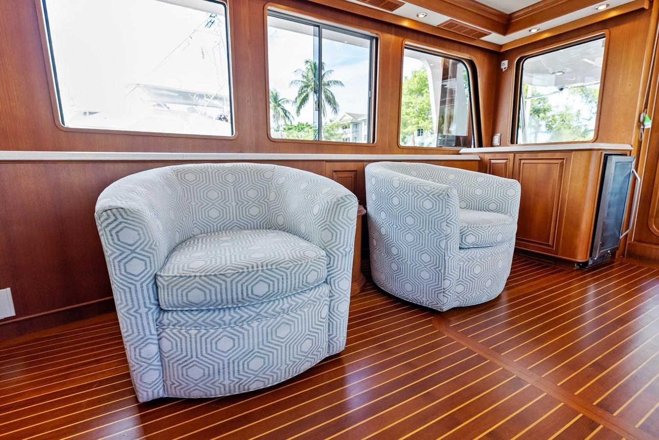 The yacht's interior features comfortable, stylish seating with a view of the outside through large windows. aboard EL LEGADO Yacht for Sale