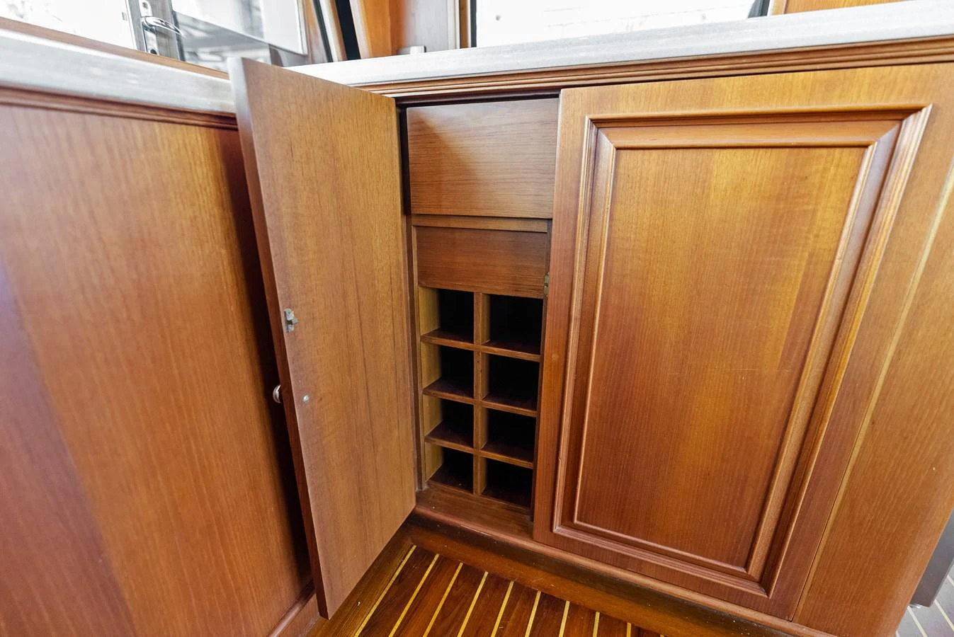 The image showcases a wooden wine storage cabinet with open and closed doors, highlighting the craftsmanship and storage capacity. aboard EL LEGADO Yacht for Sale