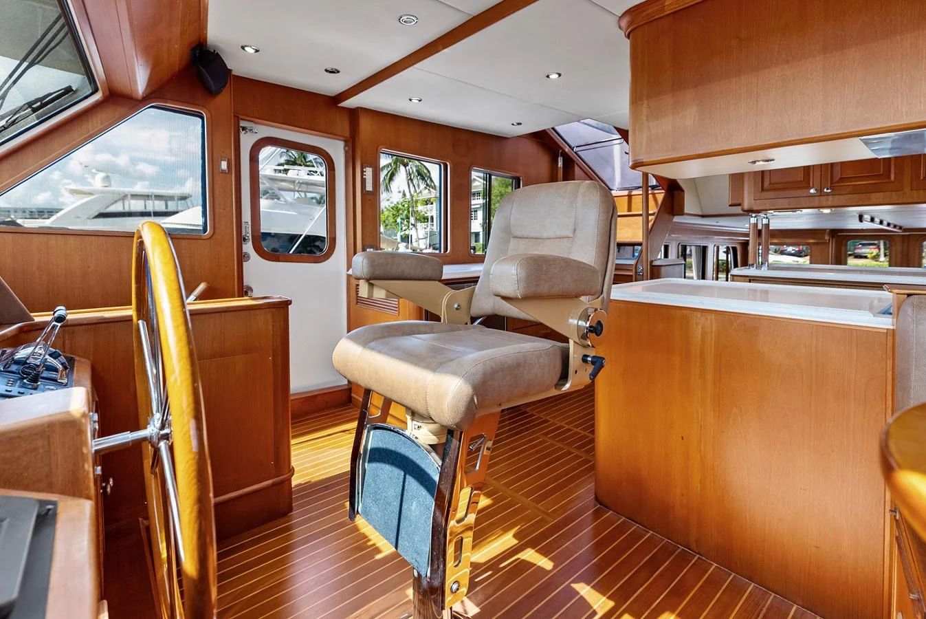 The helm area features plush seating and a beautifully crafted wooden steering wheel, offering a blend of comfort and functionality. aboard EL LEGADO Yacht for Sale