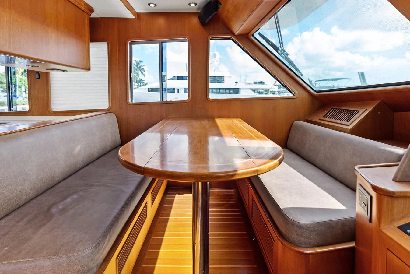 The yacht's dining area features a polished wooden table surrounded by comfortable seating with large windows providing ample natural light. aboard EL LEGADO Yacht for Sale