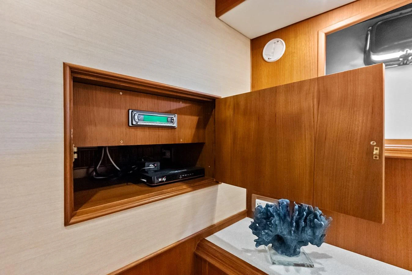 A detailed view of a cabinet with electronic equipment and a decorative item inside a yacht. aboard EL LEGADO Yacht for Sale