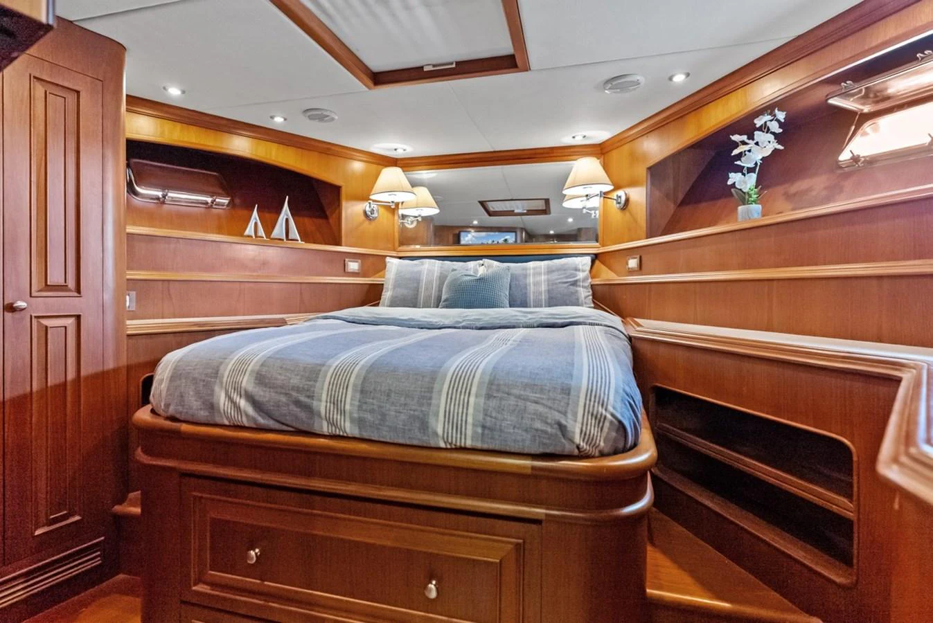 The stateroom features a luxurious bed with elegant wooden cabinetry and ambient lighting. aboard EL LEGADO Yacht for Sale