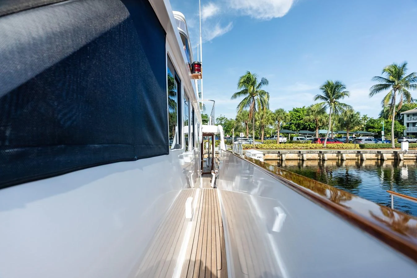 The side deck of the yacht offers a sleek walkway with a view of the serene waterfront and lush greenery. aboard EL LEGADO Yacht for Sale